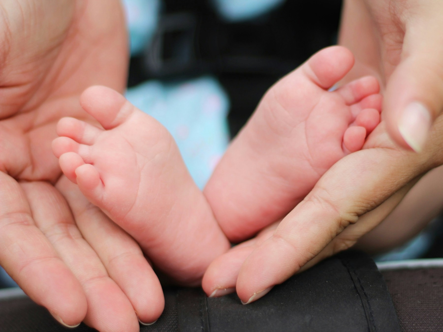 A caregiver gently cradles a baby’s feet.